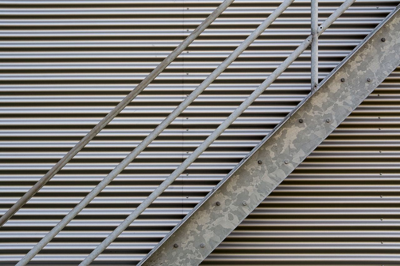 services-06 Close-up shot of metal stairs against a corrugated wall, showcasing textures.