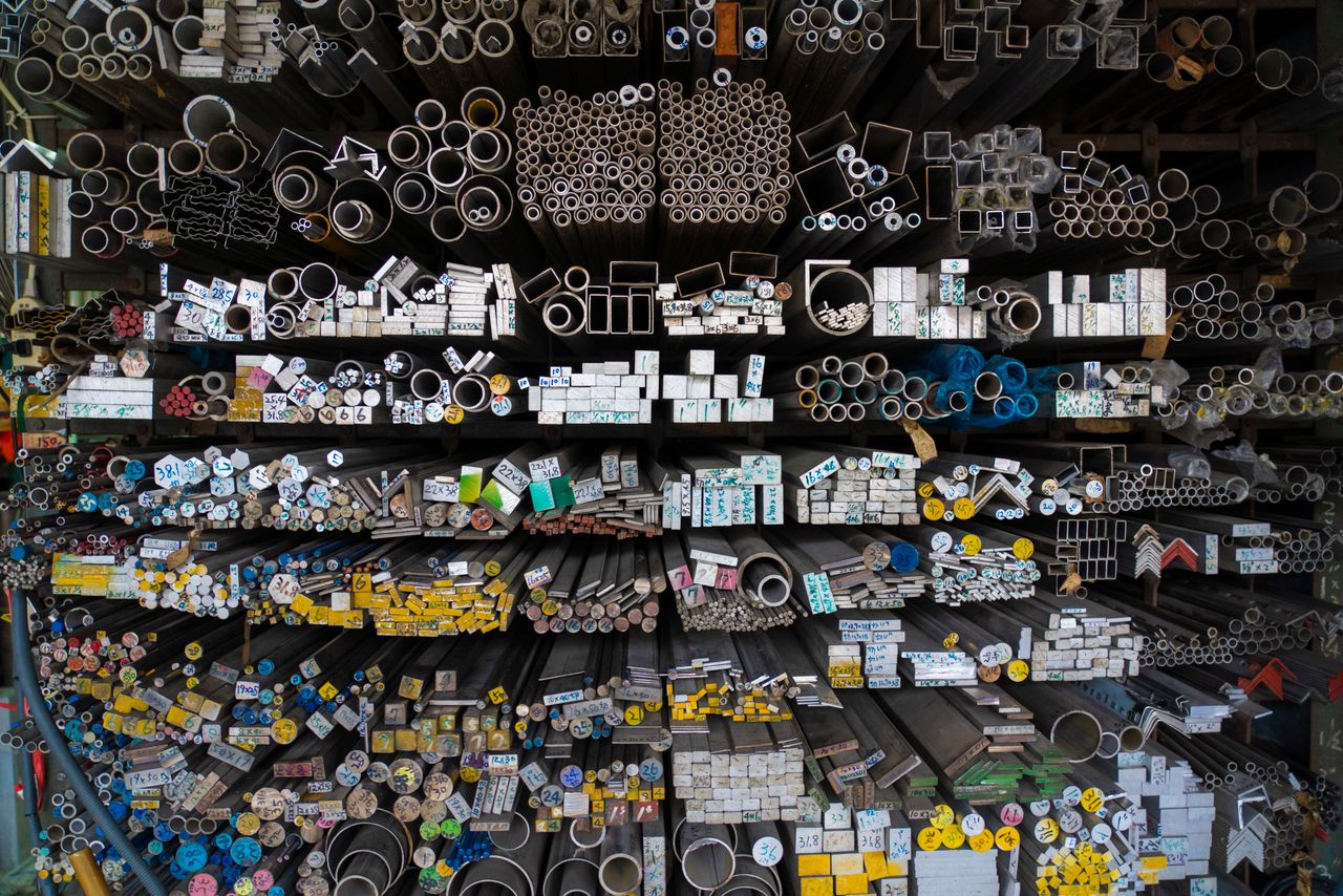about-01 Diverse collection of stacked metallic pipes and rods in a warehouse display.