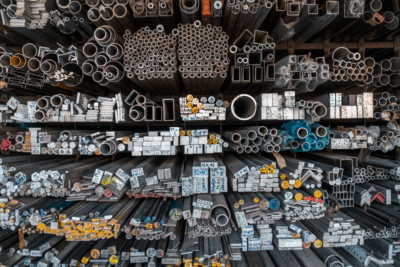 services-09 A detailed assortment of metal bars, tubes, and pipes stored on shelves in an industrial setting.