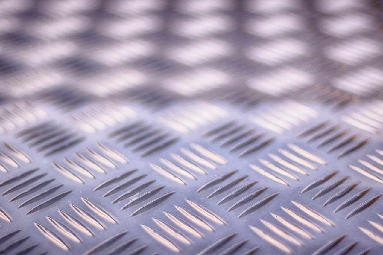 services-10 Close-up view of a textured metal checker plate surface with ribbed patterns.