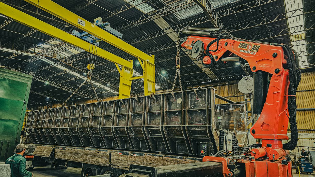 about-06 A large crane is used to load a container onto a truck inside a warehouse.