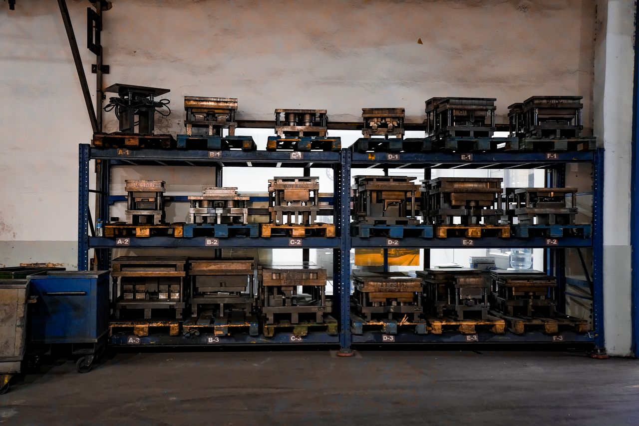 about-05 Metal molds neatly arranged on industrial shelving in a warehouse setting, showcasing order and efficiency.